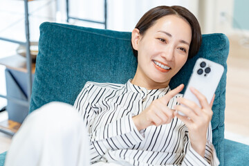 ソファに座り携帯を触る女性