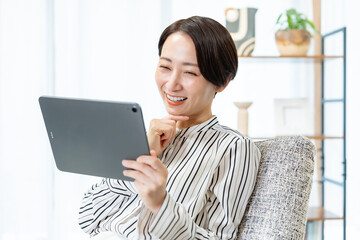 ソファに座りタブレットを持つ女性