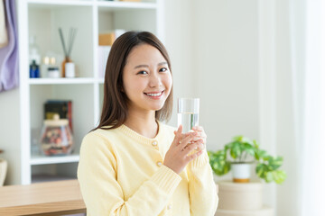 自宅でミネラルウォーターを飲む若い女性
