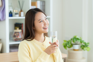 自宅でミネラルウォーターを飲む若い女性