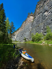 A blue and white kayak sits gracefully on the sandy shore of a beautiful river, ready to embark on an exciting adventure across the waters surface, inviting all to enjoy its splendor