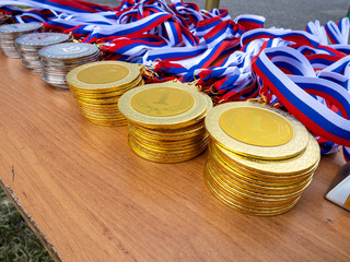 A table with a pile of gold medals and a ribbon
