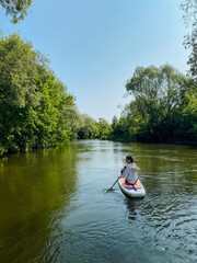A person is expertly kayaking through a rapidly moving river, delighting in this leisurely pursuit and taking in the breathtaking natural beauty that surrounds the tranquil water