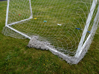 A soccer goal with a net that is torn and has a piece of string on it
