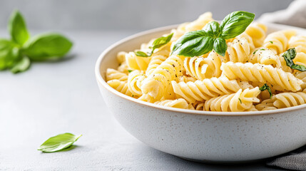 Creamy basil pasta in bowl with fresh herbs and soft shadows creates delightful ambiance