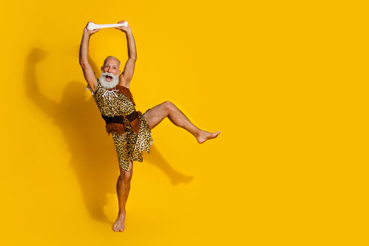 Full length photo of cool wildman dressed leopard skin having fun rising mammoth bone mockup space isolated yellow color background