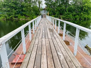 A beautifully crafted wooden bridge spans gracefully over a serene body of water, with lush trees thoughtfully positioned in the background, enhancing the picturesque view