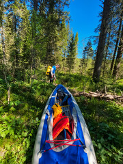 A joyful person stands beside a vibrant, colorful kayak in the lush woods, surrounded by tall, majestic trees, eagerly anticipating an exciting outdoor adventure on the serene water surface