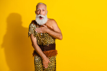 Photo of ancient aged shy caveman arms cover body empty space wear leopard skin clothes isolated on yellow color background
