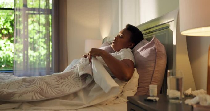 Sick, tired and black woman in bed in home with allergies, flu symptoms and infection in morning. Health, wellness and person with fatigue, upset and weak in bedroom with illness, pain and resting