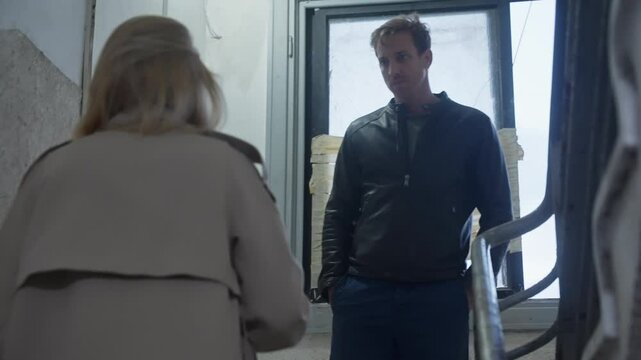 Woman and man meet in staircase of building to exchange envelope with cash or payment for service. Dark dirty deal or business. Fraud and collusion. Insider information and bribery. Spy network