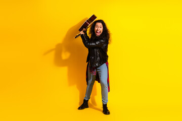 Energetic man in a leather jacket holding a guitar with a joyful expression on a vibrant yellow background