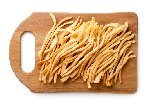Pieces of smoked cheese on a kitchen board on a white background. Top view. Chechel cheese isolated