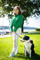 girl and her dog. A girl in sunglasses, green shirt, and white pants trains and hugs her dog in lush Norwegian greenery. A sincere moment of connection, trust, and shared movement.