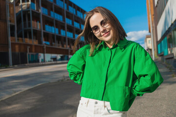 A sunny moment in Norway: a girl in sunglasses and a summer look stands still while a young man walks past. A contrast of stillness and motion in urban nature.