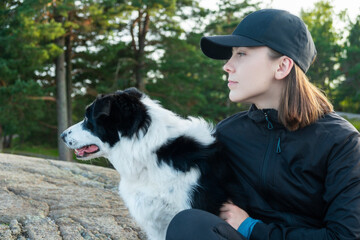 young woman with a dog. woman sits on snow covered rock along lake with her dog in Norway