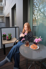 beautiful teenager girl  with smartphone and cup of tea on balcony