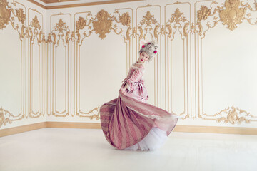 Elegant young woman in classic baroque attire gracefully poses in a lavish historic palace setting