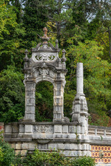 Fototapeta premium Massandra Palace of Emperor Alexander III. Stone archway stands amidst lush greenery, showcasing intricate carvings and classical architectural details. Yalta, Crimea