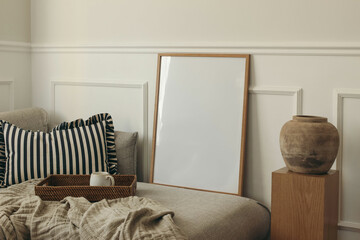 Empty wooden picture frame on sofa, pillow. Wicker tray with cup of tea, coffee. White panelled...