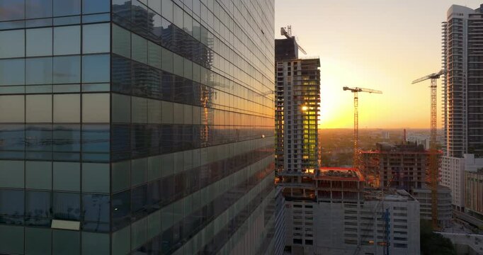 Aerial view of new developing residence in American urban area at sunset. Tower cranes at industrial construction site in Miami, Florida. Concept of housing growth in the USA.