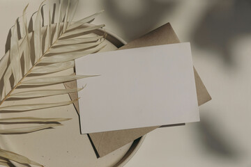 Blank horizontal greeting card, invitation mockup, craft envelope in sunlight, beige table...