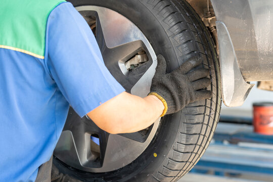 Action from back of a technician man is installing a car wheel after new tire replacement. Working person scene, selective focus.