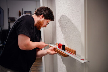 Man Using Spirit Level for Wall Mounting Project at Home