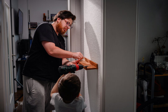Father and Son Installing Shelf Together at Home - Powered by Adobe