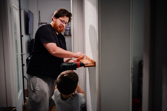 Father and Son Installing Shelf Together at Home