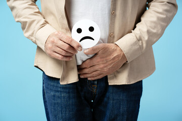 Senior man suffering from abdominal pain holding sad face emoji