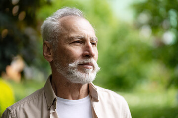 Senior man enjoying nature and looking away thoughtfully in park outdoors