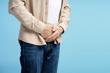 Senior man experiencing abdominal discomfort on blue background