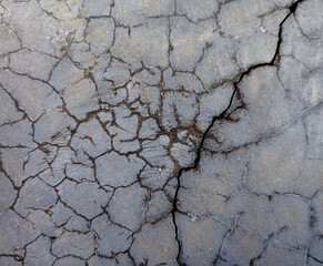 Fototapeta premium detailed close-up of severely cracked pavement, showcasing intricate patterns of damage and deep fissures, reflecting wear, tear, and the passage of time.