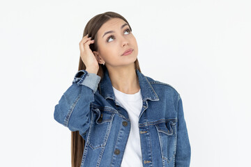 Young beautiful girl with long brown hair wearing jeans coat. freelancer looking away with confused disappointed expression, scratching head. student not remembers information for exam