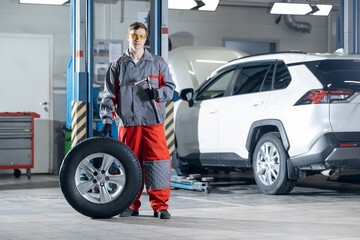 Worker changing car wheel at tire in service garage