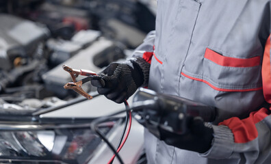 Auto mechanic using diagnostic tool for control battery lvl of car in workshop