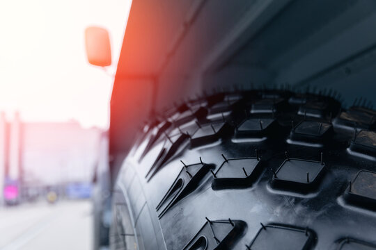 Fototapeta Close-up of heavy-duty truck tire with tread pattern on industrial road