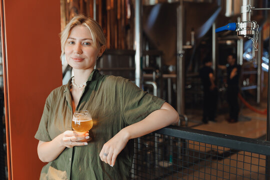 Worker Female adult in brewery factory holding fresh beer glass