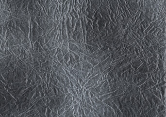 Abstract background texture made of crumpled paper with deep folds and a gray-graphite shade. Crumpled black and white transparent paper. The background is made of crumpled tracing paper.