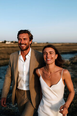 Obraz premium Romantic couple walking by the sea in warm sunset light, elegant summer vacation lifestyle 