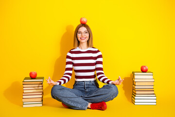 Young Woman in Striped Sweater Sitting Calmly with book and Apples on a Vivid Yellow Background...