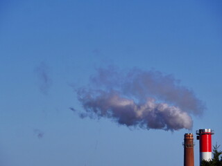 A large cloud of smoke is rising from a red and white tower