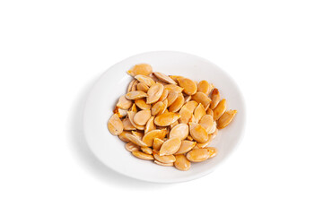 Pumpkin seeds on a white plate on a white background in a top view