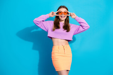 Stylish woman wearing colorful outfit and playful glasses against blue background showcasing trendy casual fashion