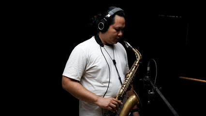 Musician Playing Saxophone in Recording Studio on dark black isolated background