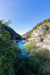 Fototapeta premium Pristine turquoise waters of Lake San Domenico framed by steep rocky mountains in Abruzzo on a clear summer day.