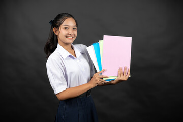 Obraz premium An Asian high school girl in her school uniform stands in a studio background, thinking about how her daily efforts will help her get into a top university next year.
