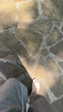 persona che cammina a piedi nudi all'aperto su una pavimentazione in pietra