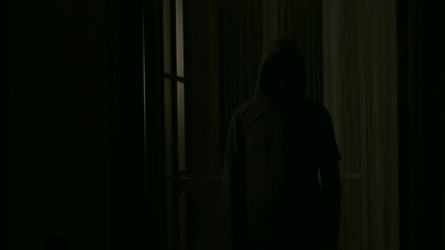 A scary video with a black silhouette of a killer or maniac in a house approaching the victim, first-person view.